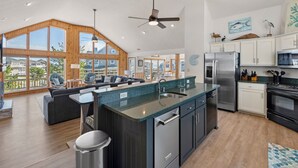 A spacious kitchen with a large island, stainless steel appliances, and a view of the surrounding area. - The Wheelhouse: Pool and Hot Tub | 500ft. to Beach (Corolla)