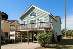 A two-story house with a balcony, a small porch, and a fish decal on the front. - Crabby Patty: Pool Access | Short Walk to Beach (Nags Head)