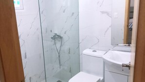 Une salle de bain avec une douche à parois de verre, des toilettes blanches et un lavabo avec un miroir au-dessus.