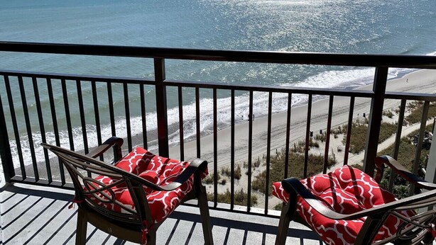 A balcony with two chairs and a view of the ocean and beach. - 1510 Pearl on the Beach. Pet Friendly. Oceanfront. (Myrtle Beach)