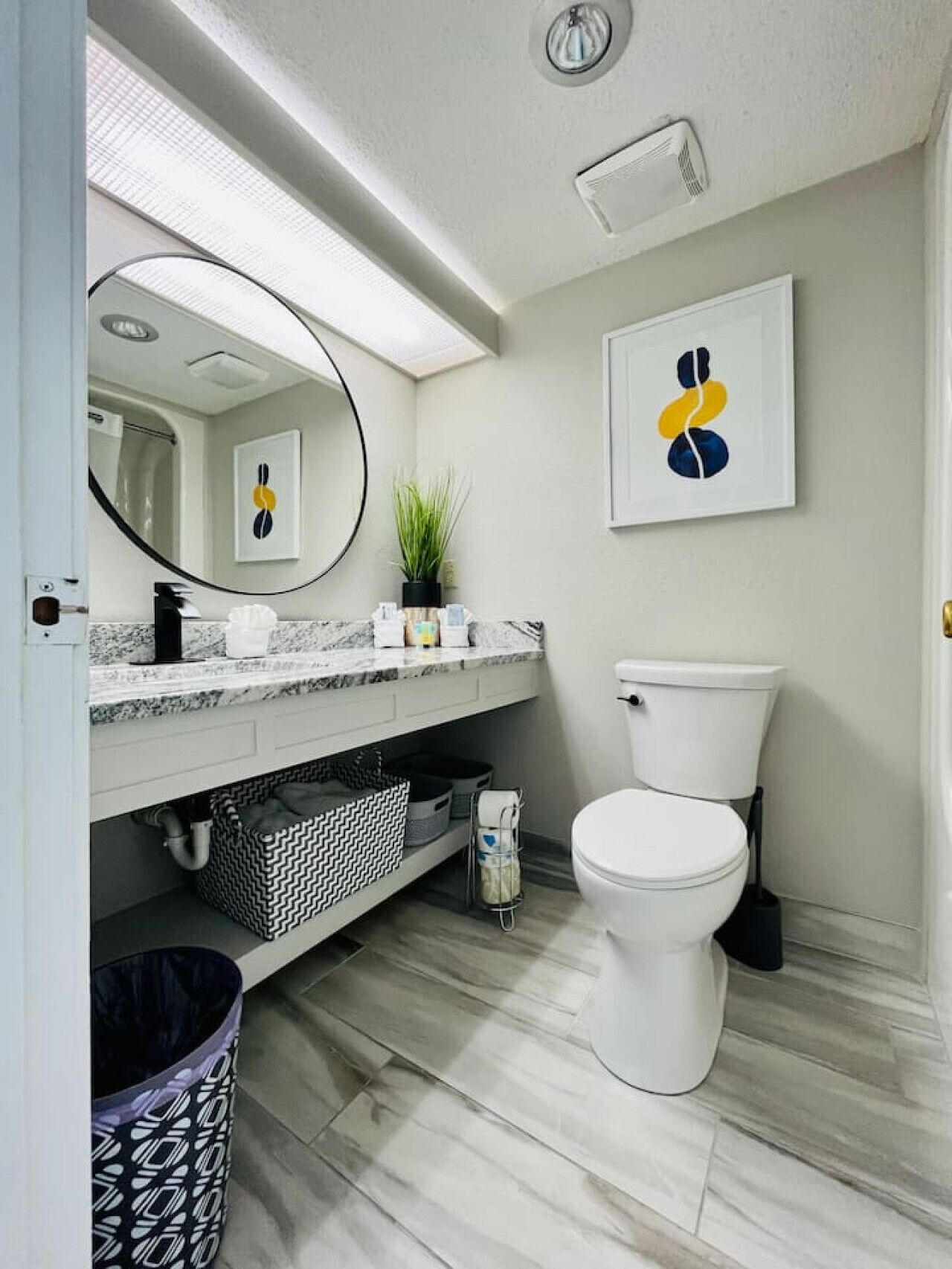 A modern bathroom with a white toilet, a sink with a mirror, and a shower area.