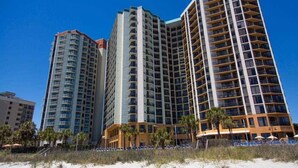 A beachfront hotel with multiple high-rise buildings, featuring balconies and a sandy beach area. - 1510 Pearl on the Beach. Pet Friendly. Oceanfront. (Myrtle Beach)
