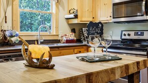 A kitchen with wooden cabinets, a stainless steel microwave, and a window with a view of greenery. - Cozy Cottage minutes from Wineries & 5 miles to Dahlonega Square (Dahlonega)