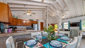 Una cocina amplia con armarios de madera, una isla grande y un comedor preparado para seis personas, con platos azules y blancos.