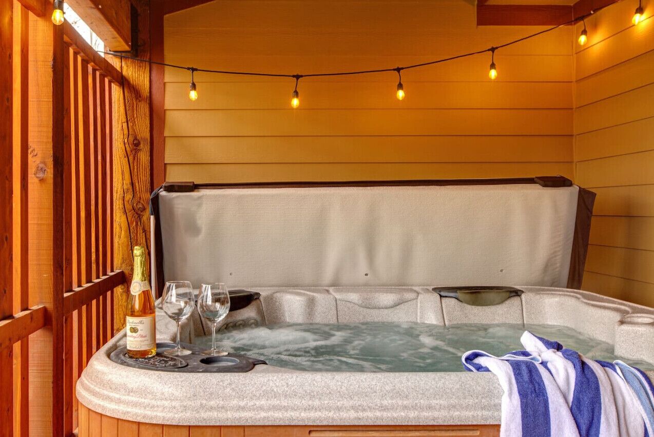 Un bain à remous avec un siège en pierre, une bouteille de vin et deux verres.