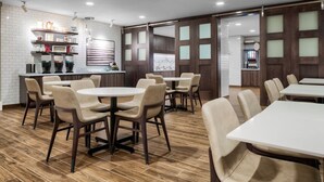 A modern restaurant with a brick wall, wooden flooring, and a mix of round and square tables. - Residence Inn by Marriott Decatur Emory Area (Decatur)