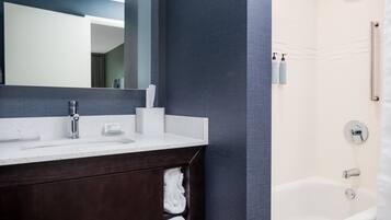 A modern bathroom with a dark wood vanity, a white sink, and a bathtub.