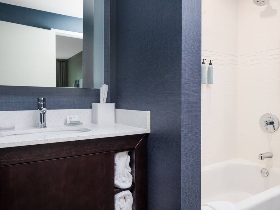 A modern bathroom with a dark wood vanity, a white sink, and a bathtub.