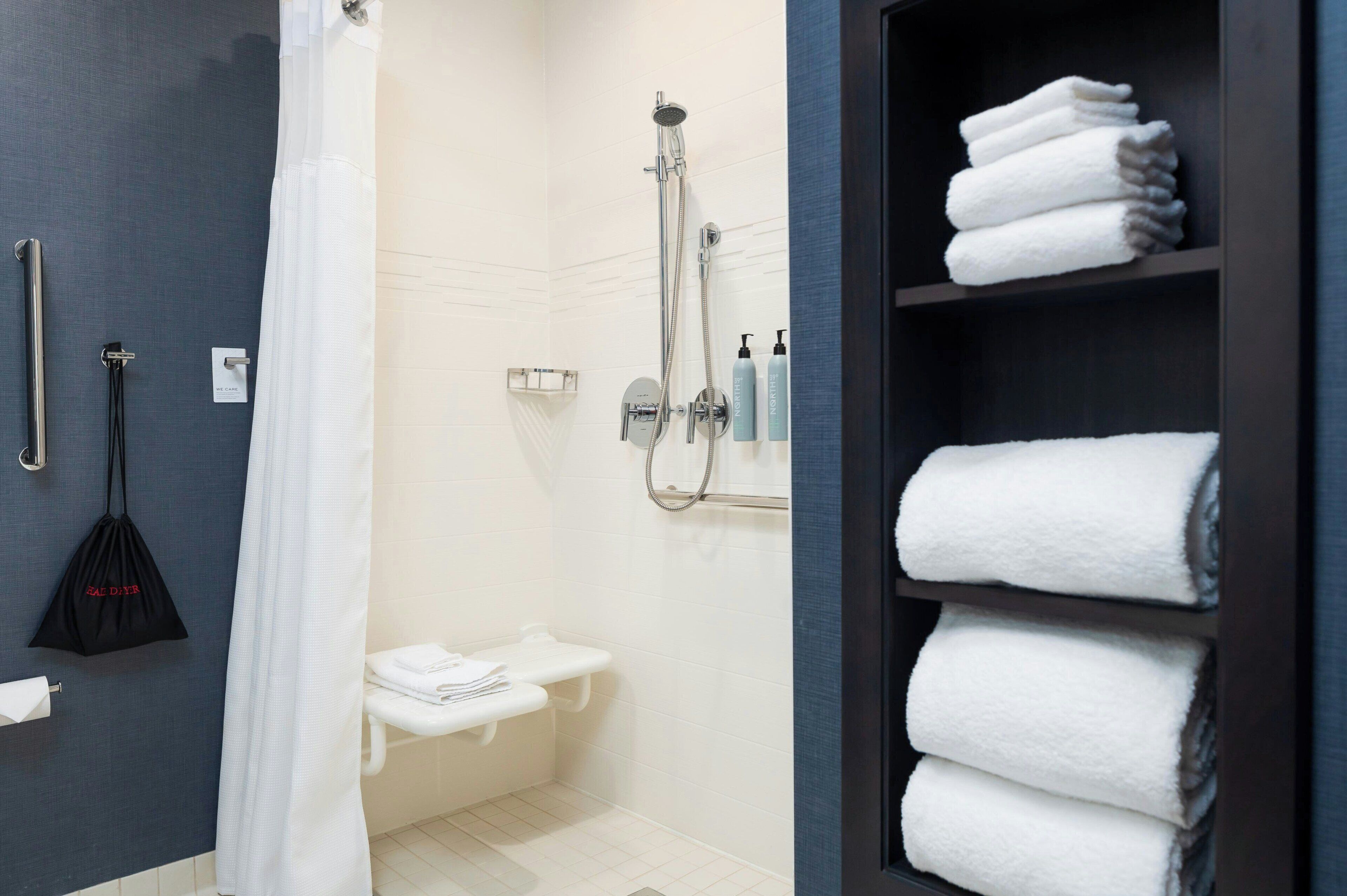 A modern bathroom with a shower, toilet, and towel rack.