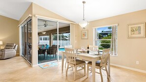 A spacious living room with a dining area, a pool, and large windows. - Pet-friendly villa w/fenced in yard, bikes & electric heated pool! Villa Royal Ann - SWFL Rentals (Cape Coral)
