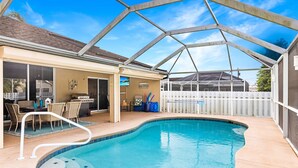 A swimming pool with a covered patio area, including a dining table and chairs, and a fenced backyard. - Pet-friendly villa w/fenced in yard, bikes & electric heated pool! Villa Royal Ann - SWFL Rentals (Cape Coral)