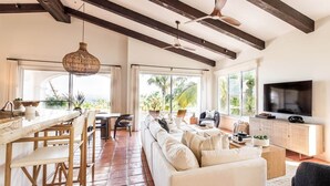 A spacious living area with a sofa, TV, and dining setup. - Peaceful Palmilla Ocean View Oasis Steps to Beach (Palmilla)