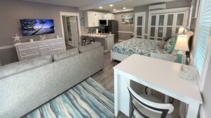 Un dormitorio moderno con cama, escritorio, sofá y televisor.