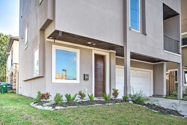 A modern two-story house with a garage, a small front garden, and a clear sky.