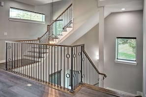 A modern staircase with a metal railing and wooden steps, leading to an upper floor.