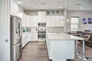 A modern kitchen with white cabinets, stainless steel appliances, and a central island.