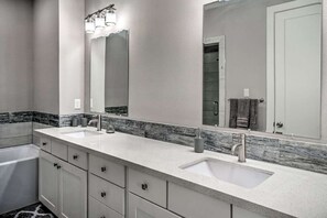 Ein modernes Badezimmer mit zwei Waschbecken, einem großen Spiegel und einem Waschtisch mit Schubladen.