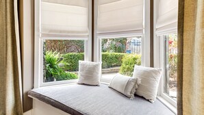A bay window with a cushioned bench, two pillows, and a view of a garden. - Charming One Bedroom Walkable to Zilker & South Lamar; Secluded multi-unit home (Austin)