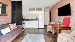A compact living space with a kitchen, a sofa, a dining table, and a TV mounted on the wall. - Charming One Bedroom Walkable to Zilker & South Lamar; Secluded multi-unit home (Austin)