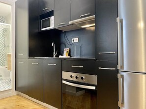 Een moderne keuken met donkere kastjes, een ingebouwde magnetron, een roestvrijstalen koelkast en een vaatwasser.