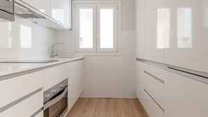 A modern kitchen with white cabinetry, a built-in oven, and a window above the sink. - Avenida América - Comfortable apartment, next to the station (Madrid)