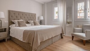 A bedroom with a large bed, bedside tables, a chair, and a window. - Avenida América - Comfortable apartment, next to the station (Madrid)