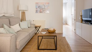A living room with a sofa, coffee table, and artwork on the wall. - Avenida América - Comfortable apartment, next to the station (Madrid)