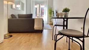 Ein Wohnzimmer mit einer Couch, einem Tisch mit Stühlen, einer Lampe und einem Blumentopf.