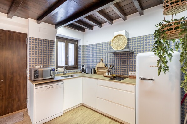 Una cocina compacta con gabinetes blancos, microondas, tostadora y refrigerador.