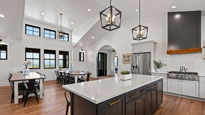 A spacious kitchen with a large island, modern appliances, and a high ceiling with skylights.