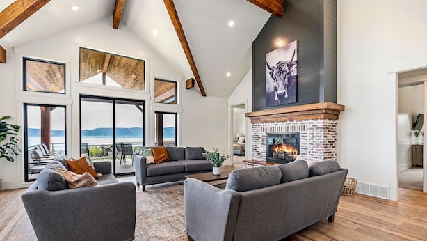 A spacious living room with a fireplace, large windows, and a view of the outdoors.