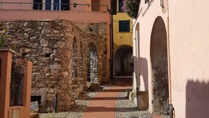 A narrow alleyway with cobblestone pavement, stone walls, and a yellow building with a window and a door. - Apartment "La Veranda": the beaches of San Lorenzo al Mare just a few steps away (San Lorenzo al Mare)