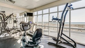 A gym with cardio machines, weight equipment, and large windows offering a view of the city. - Sky Meets The Sea: Stunning 11th Floor Unit in Summerwind West! (Navarre Beach)