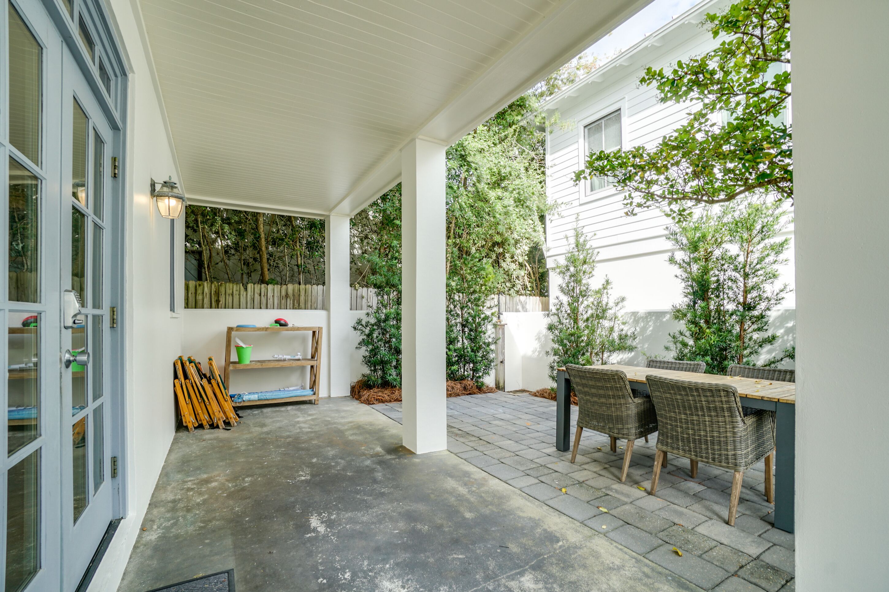 A covered patio area with a table and chairs, a wooden bench, and a wall-mounted shelf.