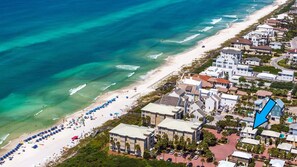 An aerial view of a coastal area with a beach, a row of white buildings, and a blue arrow pointing to a specific location. - 30A Beach House - Stillwater Cottage By Panhandle Getaways (Panama City Beach)