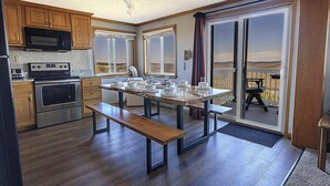 A kitchen with wooden cabinets, a microwave, an oven, and a dining table with benches. - ML 248: Your unique mountain biking haven with incredible views! (Snowshoe)