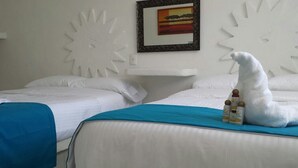 Habitación de hotel con dos camas, una pared blanca con un diseño decorativo similar a un sol, un cuadro enmarcado y una toalla blanca sobre la cama.