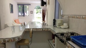 Una cocina con una isla central, estufa a gas, lavaplatos y una silla.