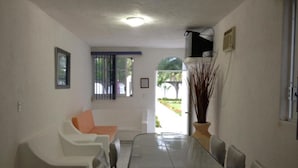 Un comedor con una mesa larga, sillas, un sofá blanco y una planta en maceta.
