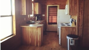 Cocina de cabaña de madera con una isla central, un refrigerador y un fregadero.