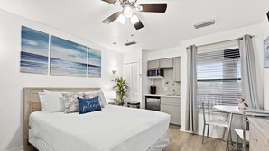 Une chambre avec un lit, un bureau et un coin cuisine.