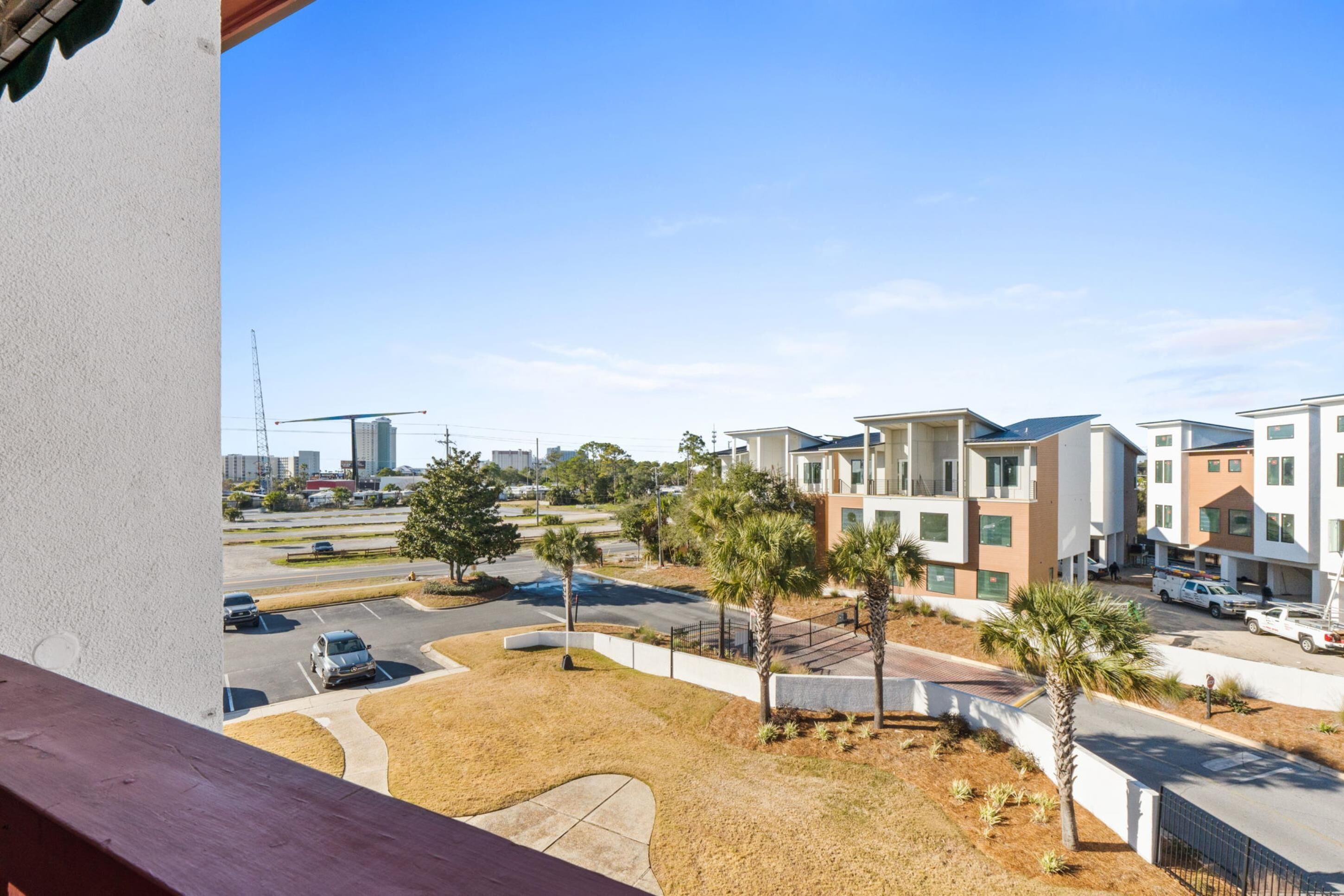 Zona residencial com edifícios de apartamentos modernos, um estacionamento e uma grua em construção ao fundo.