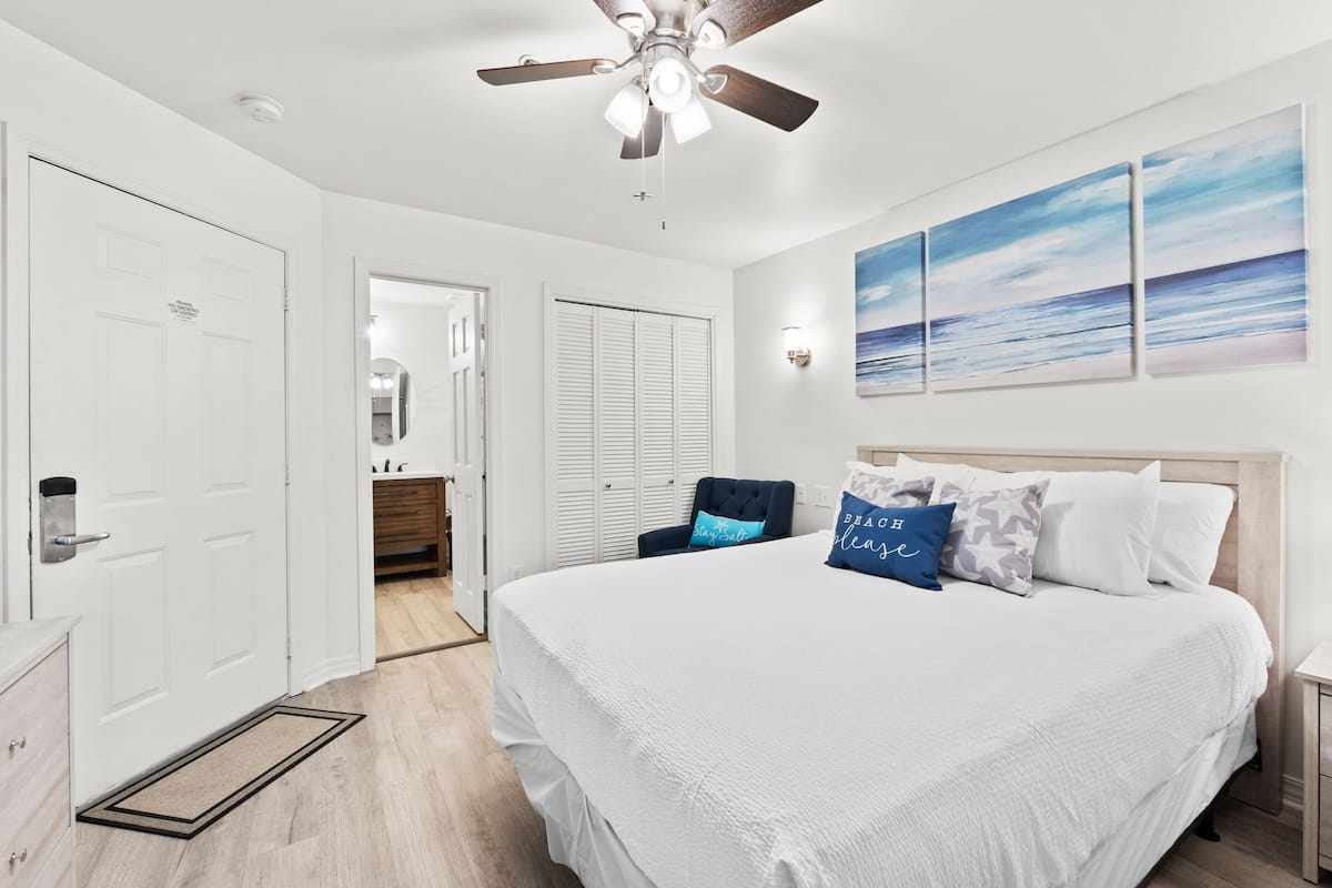 Quarto com cama grande, ventilador de teto, vista para o mar e closet espaçoso.