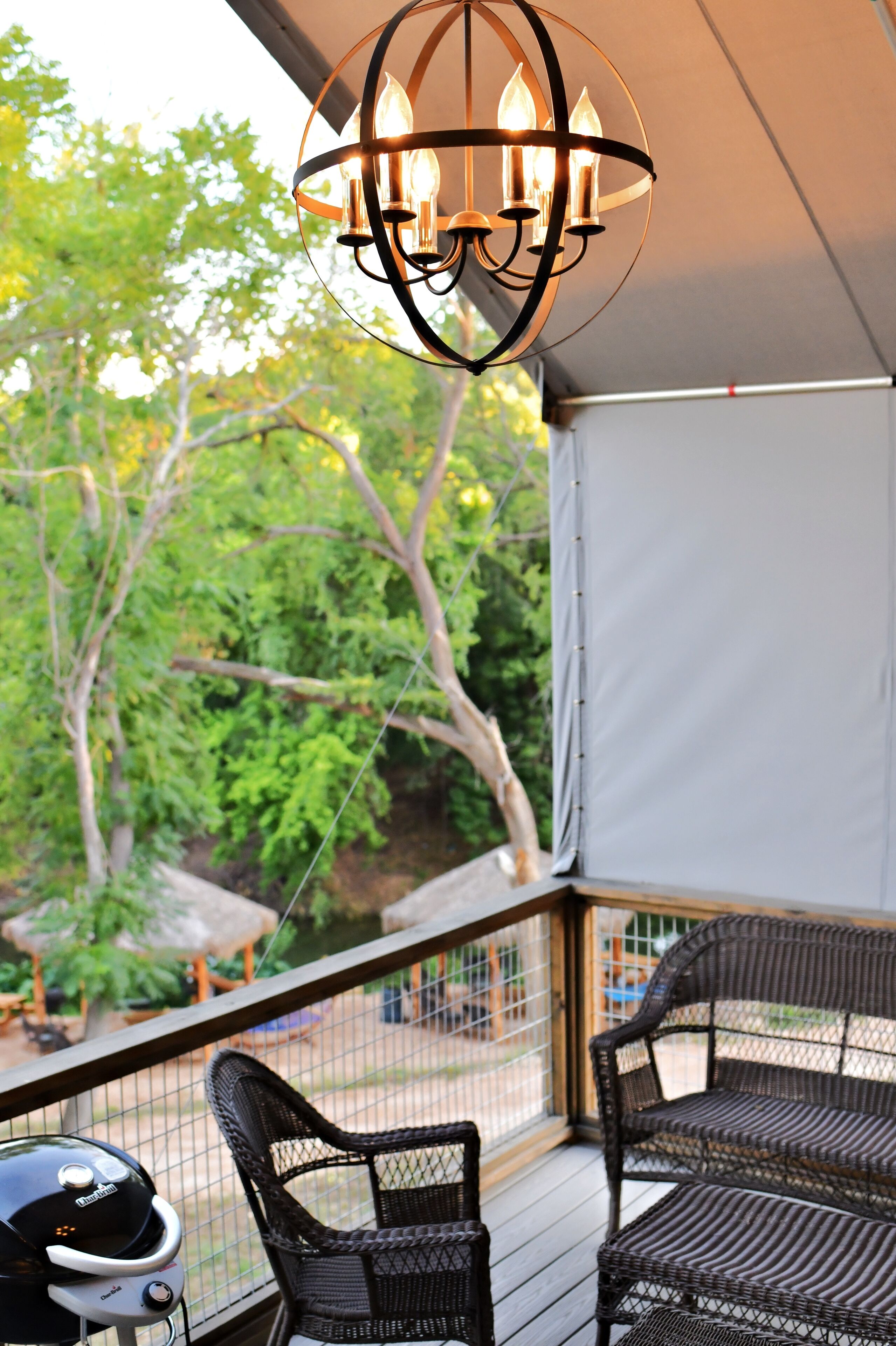 A covered outdoor area with wicker furniture and a grill.