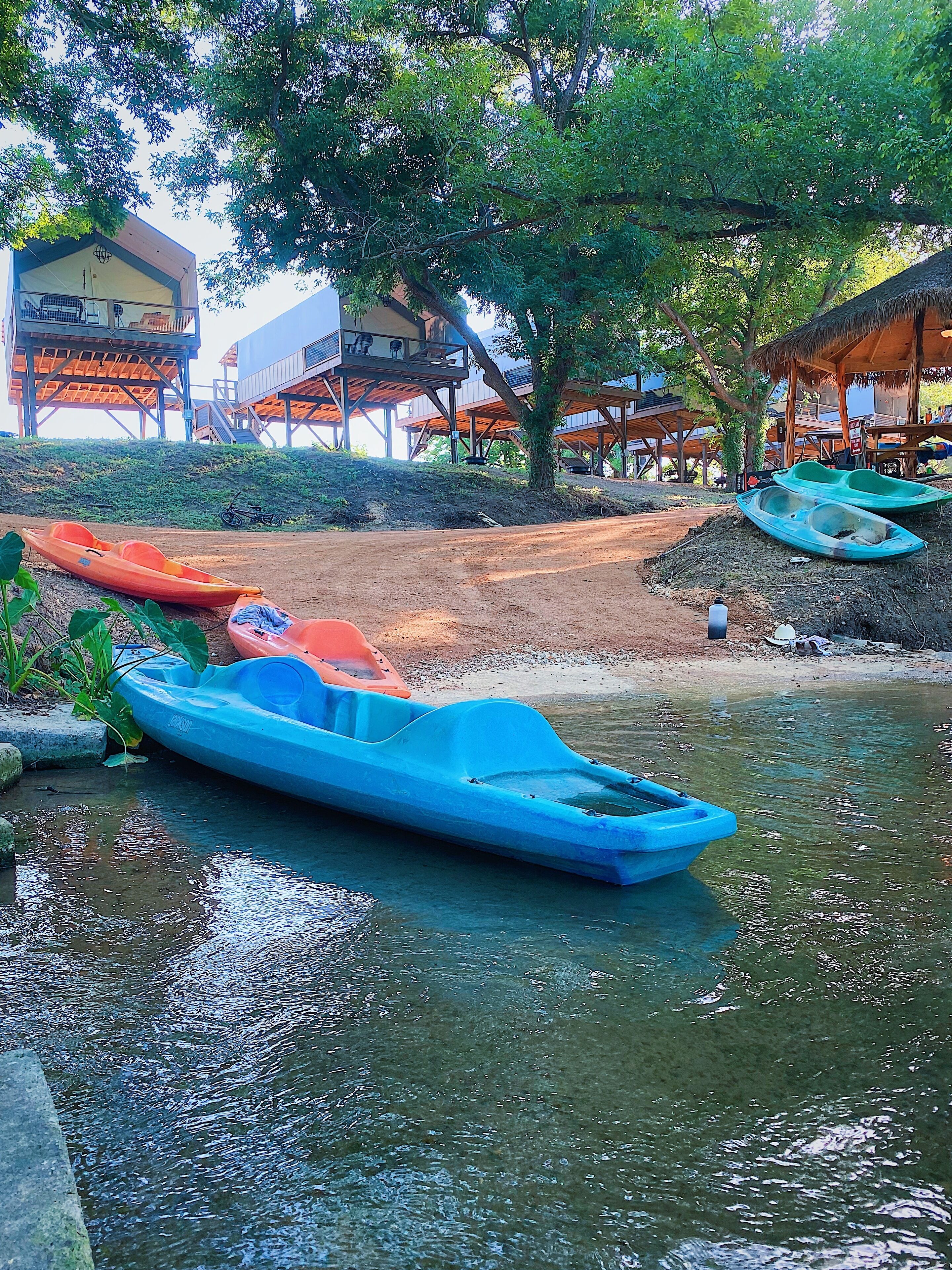 A riverside area with kayaks and a wooden structure with elevated seating.