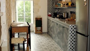 A kitchen with a round wooden table, a built-in stove, and a refrigerator.