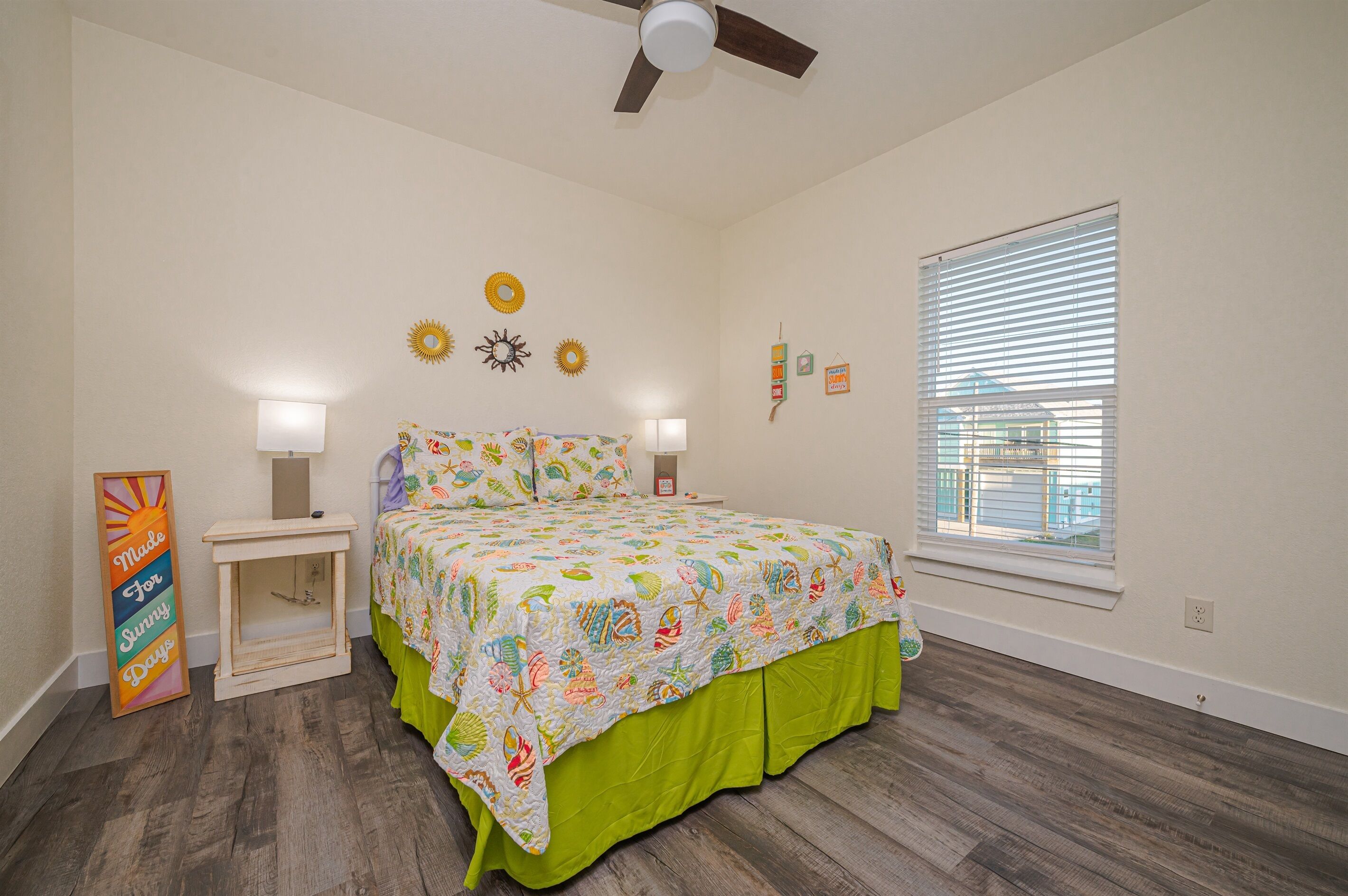 A bedroom with a bed, bedside tables, a ceiling fan, and a window with blinds.