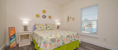 A bedroom with a bed, bedside tables, a ceiling fan, and a window with blinds.