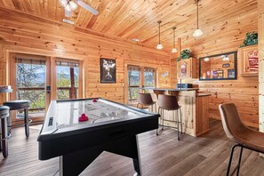Un intérieur en bois comprenant une table de billard, un coin bar et des sièges.