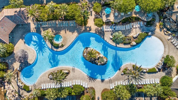 Vista aérea de un resort con varias piscinas, tumbonas y palmeras.